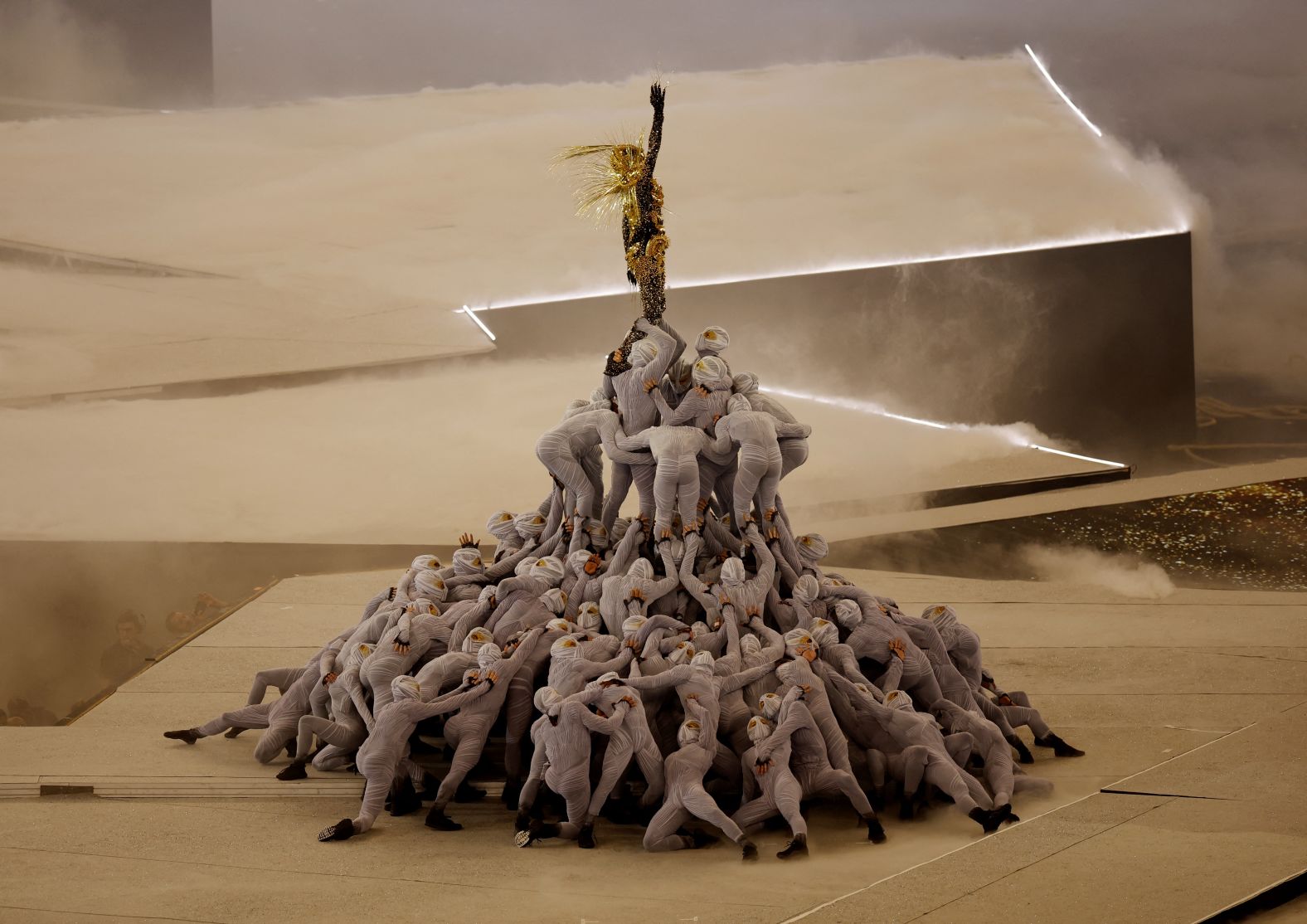 A Golden Voyager inspired by references from French history stands atop a pile of masked dancers as the last Olympic ring is raised above the stage