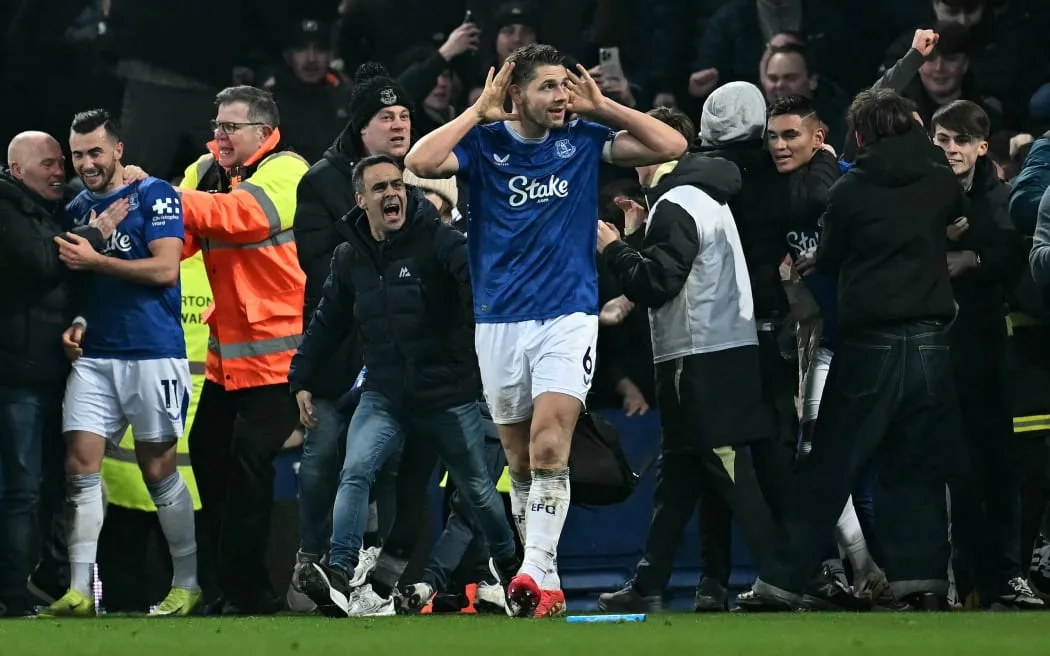 Everton captain James Tarkowski is mobbed by fans as he celebrates scoring the equaliser against Liverpool