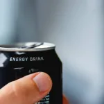 close up of a hand holding a can of energy drink