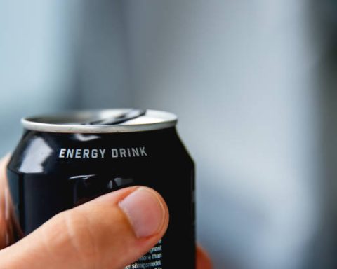 close up of a hand holding a can of energy drink