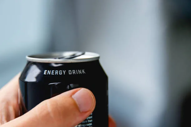 close up of a hand holding a can of energy drink